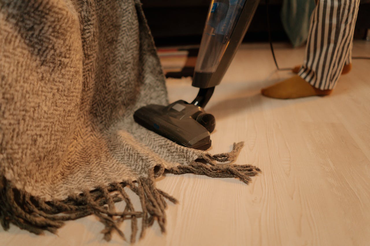 services-03 Close-up of vacuum cleaner cleaning a woolen blanket on the floor indoors.